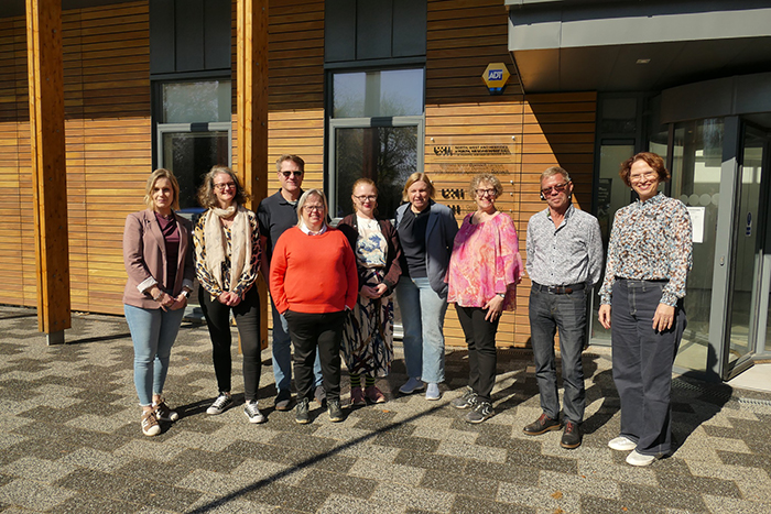 A group of people standing posing for a photo outside a university campus