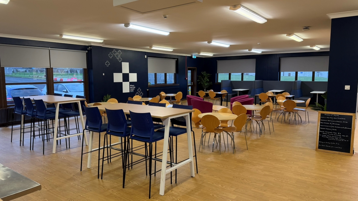 picture of Thurso canteen. Blue walls, with UHI plus sign, tables and chairs, serving counter