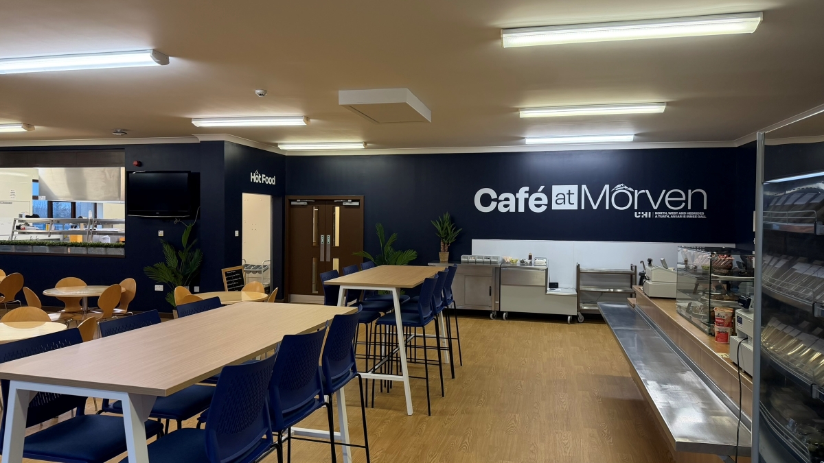 picture of Thurso canteen. Blue walls, with Cafe at Morven logo, tables and chairs, serving counter
