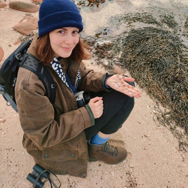 Student Ambassador Claire Parisis on a beach holding shells