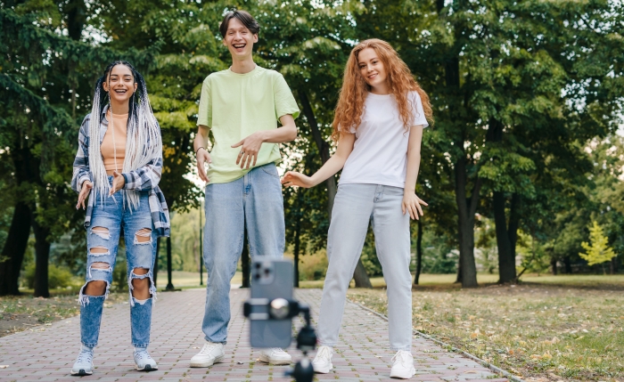 3 young people creating online content for their channel in the park with a mobile phone