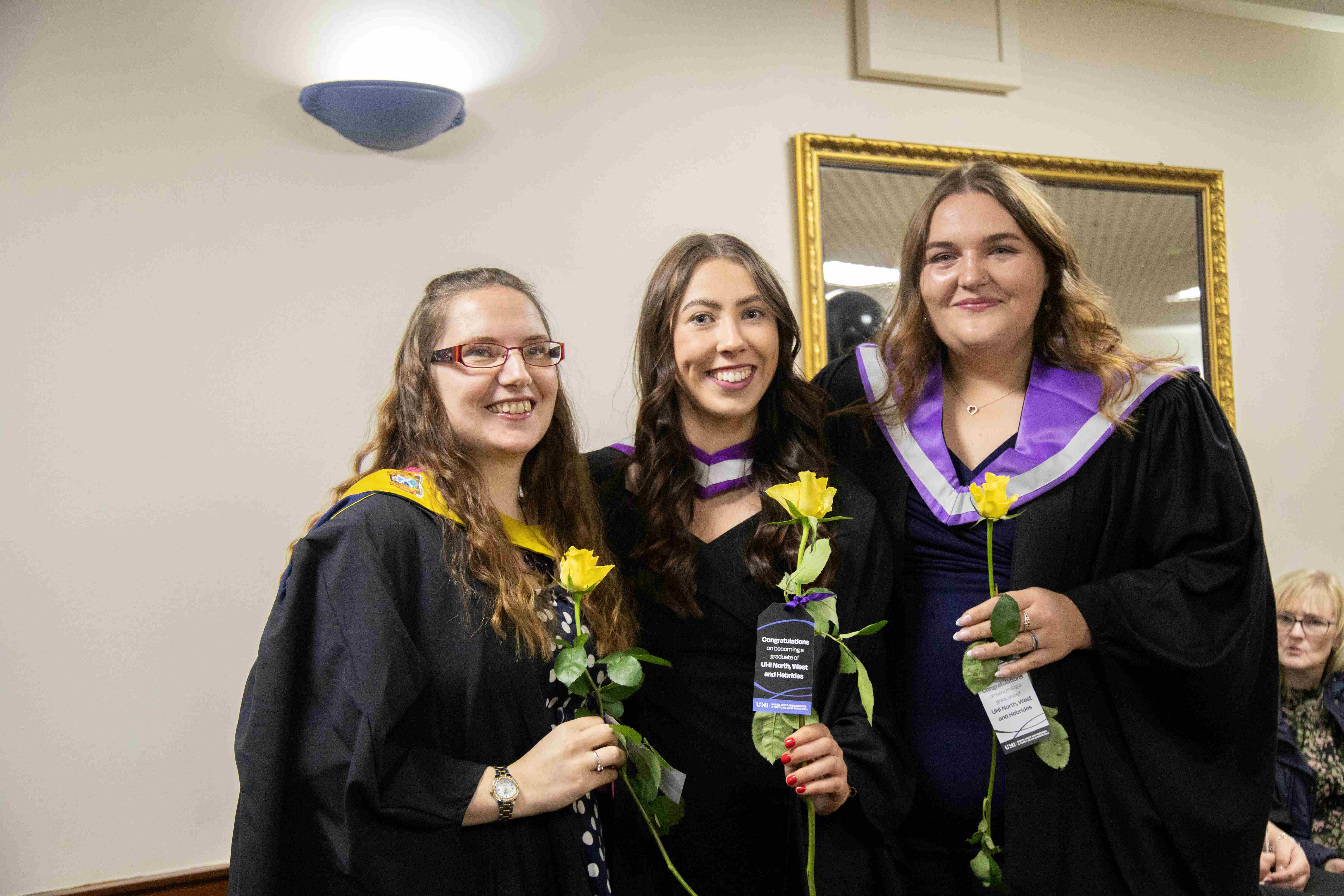 Three graduates holding the roses