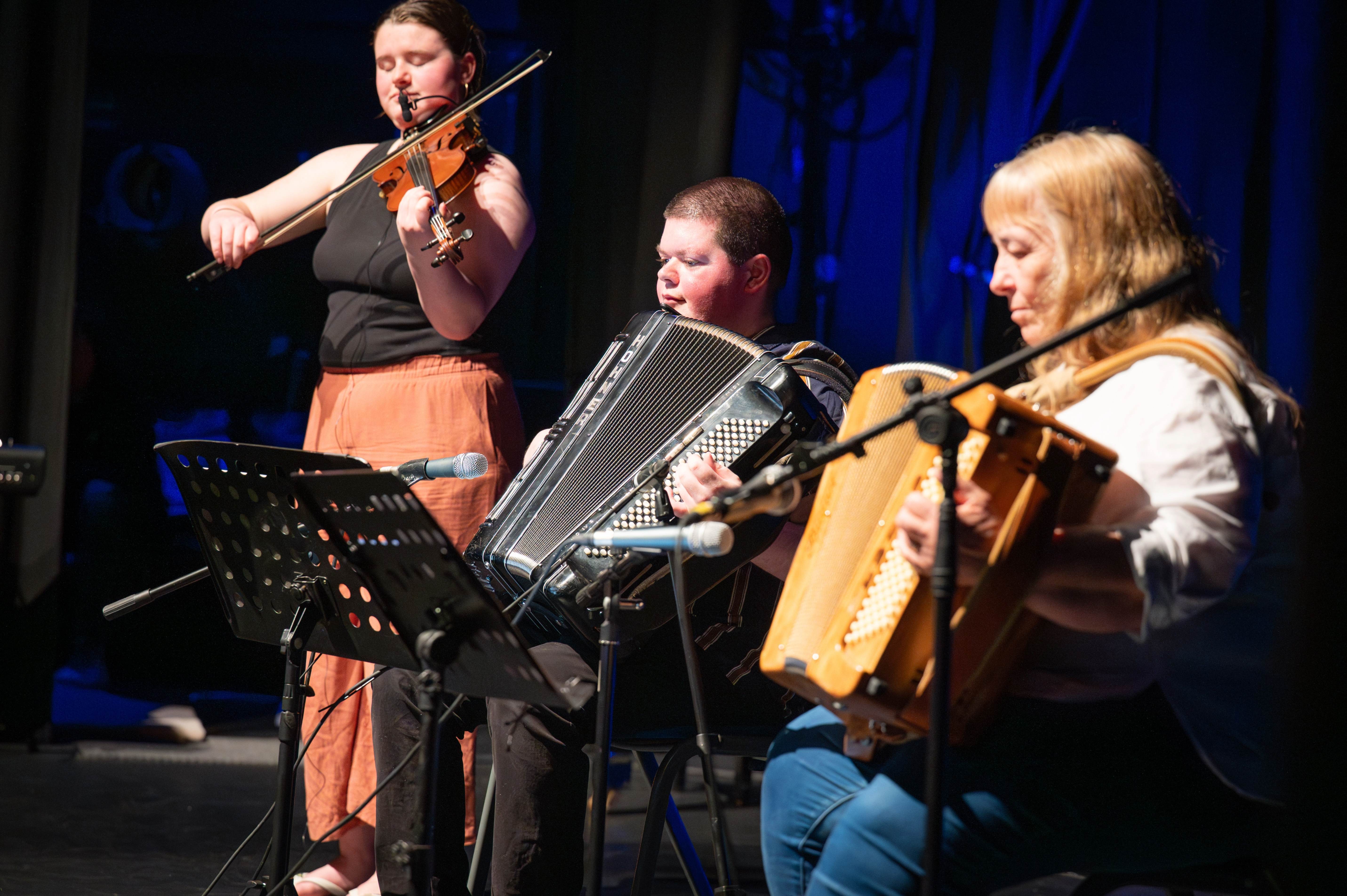 Three people performing music on a stage Three people performing music on a stage