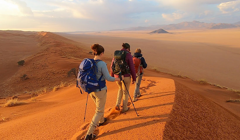 Students walking across the peak of a dune in a Namibian desert