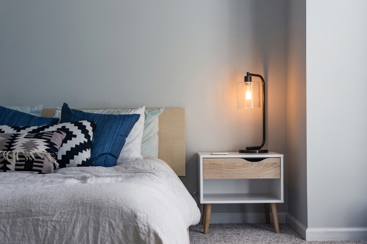 Modern bedroom with blue pillows, a bedside table, and a lit lamp. Modern bedroom with blue pillows, a bedside table, and a lit lamp.
