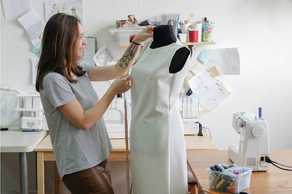 Fashion student measuring dress on mannequin