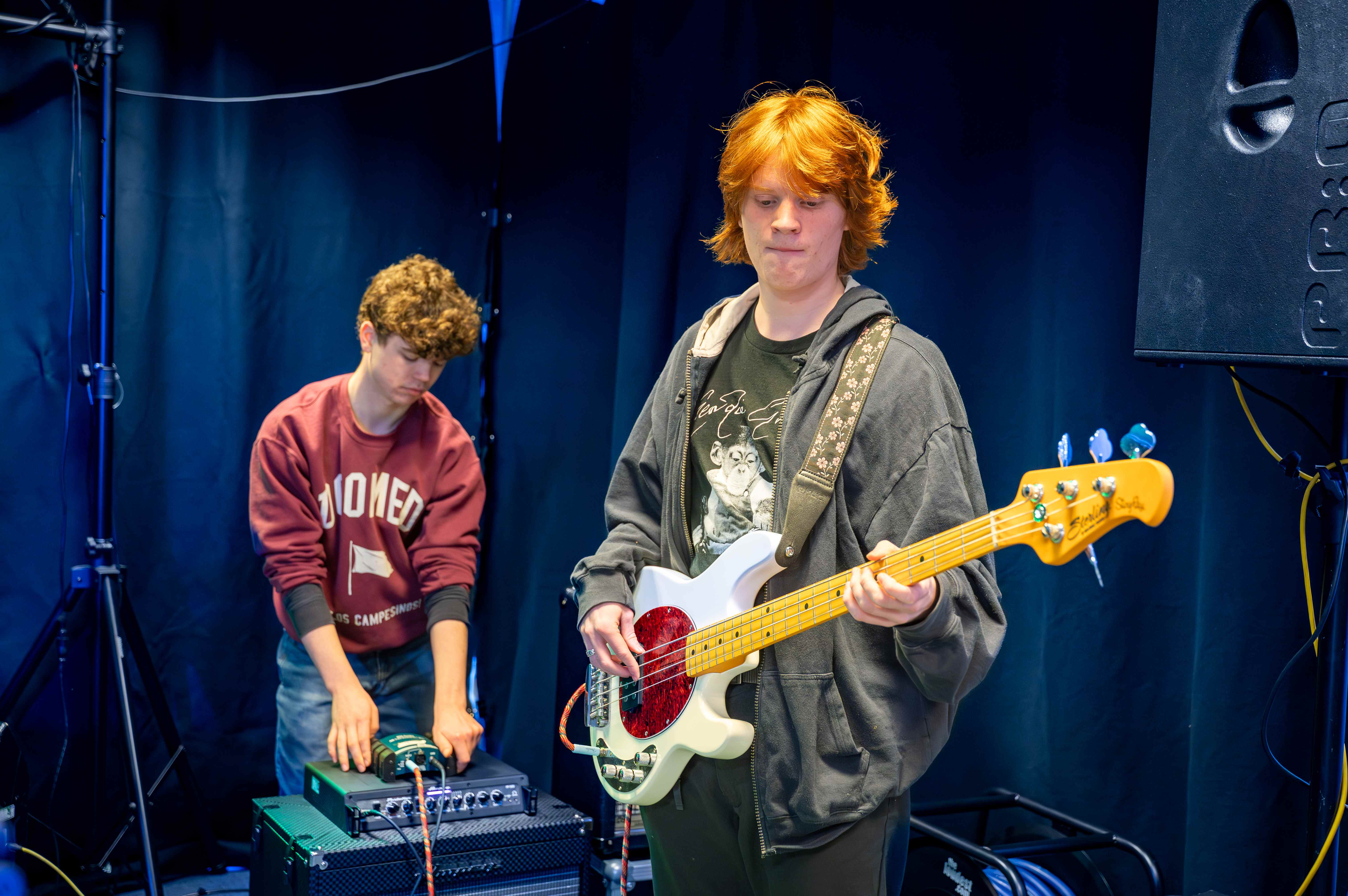 two male students. One on guitar and one mixing sound