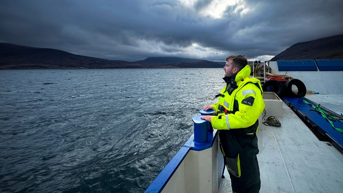 Modern Apprentice Andrew Logan looking out at sea from the deck of a vessel under a stormy sky.
