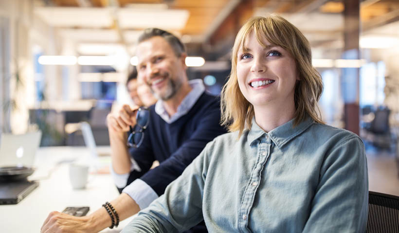 man and woman sat at computer smiling towards camera man and woman sat at computer smiling towards camera