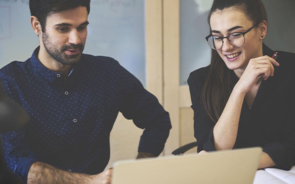 A male and female student studying at a laptop