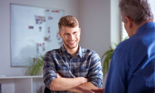 man wearing check shirt sitting smiling